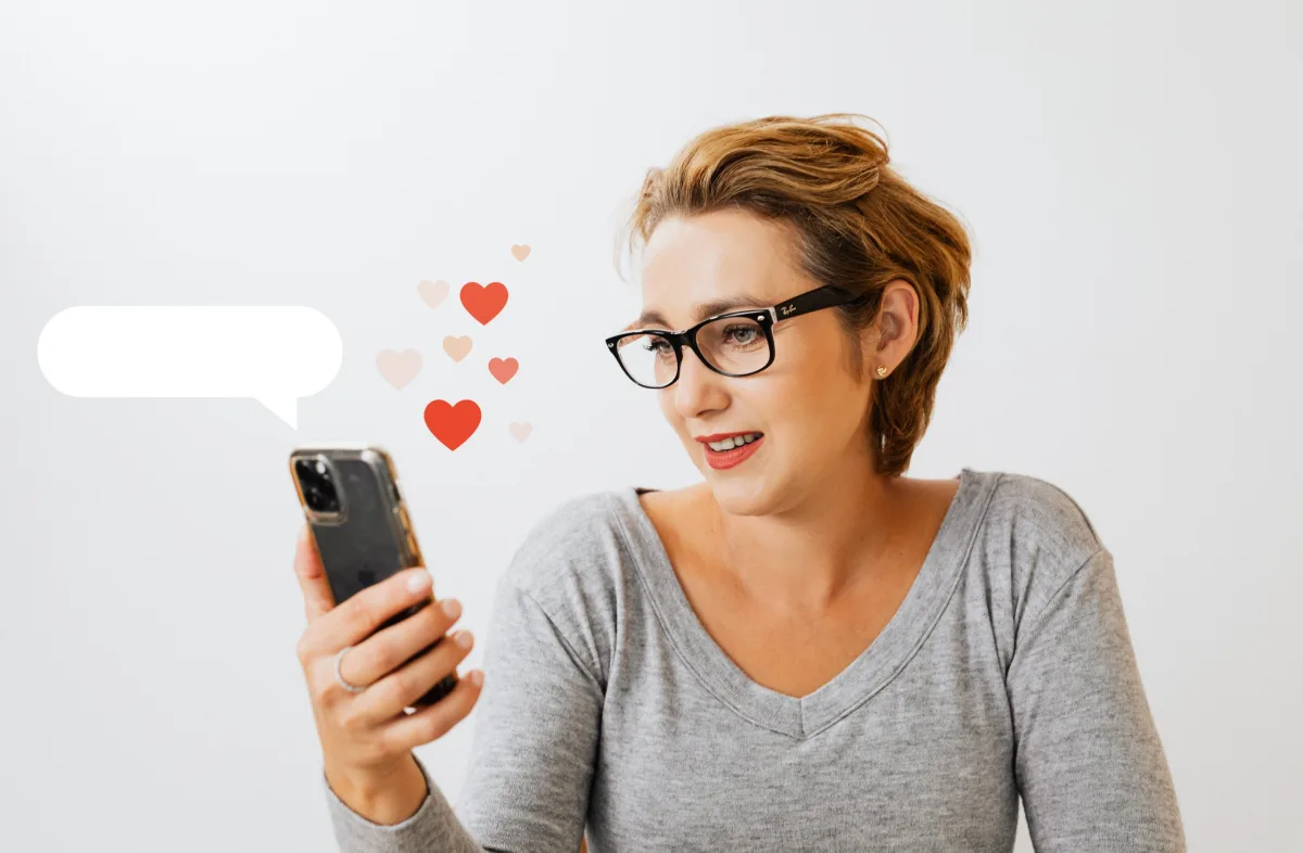 Woman wearing glasses holding a smartphone, with heart icons and a message bubble next to her.