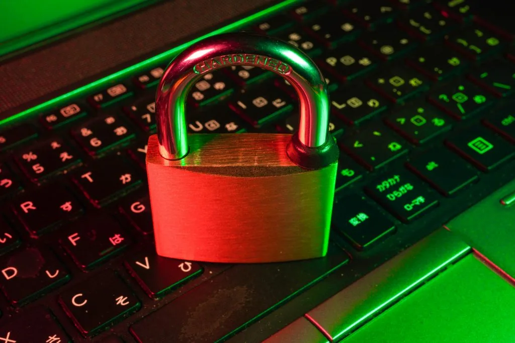 Padlock on a laptop keyboard under red and green light, symbolizing cybersecurity and data protection in Poland’s growing tech sector.