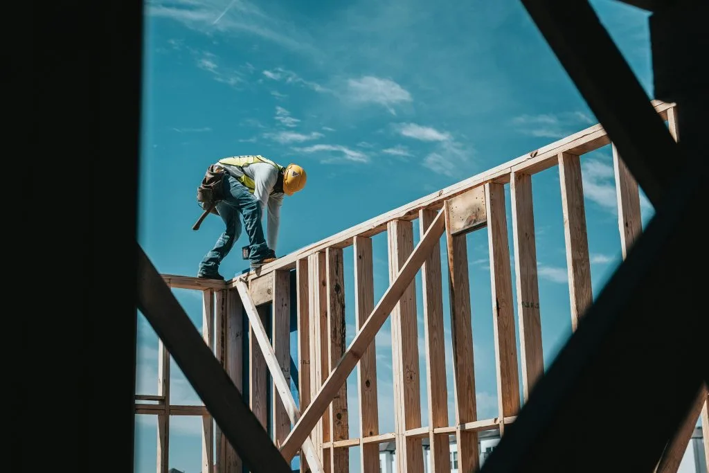 Construction worker building a wooden structure under a blue sky, representing Poland’s shift toward green and sustainable building materials.