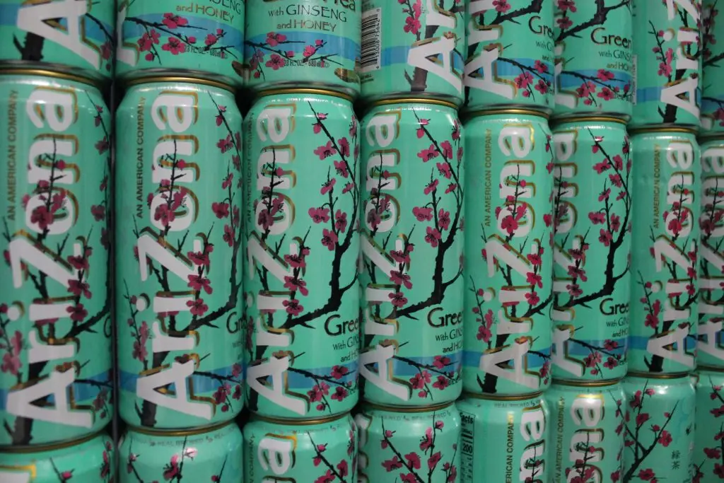 A row of Arizona Green Tea cans with cherry blossom design stacked on a shelf