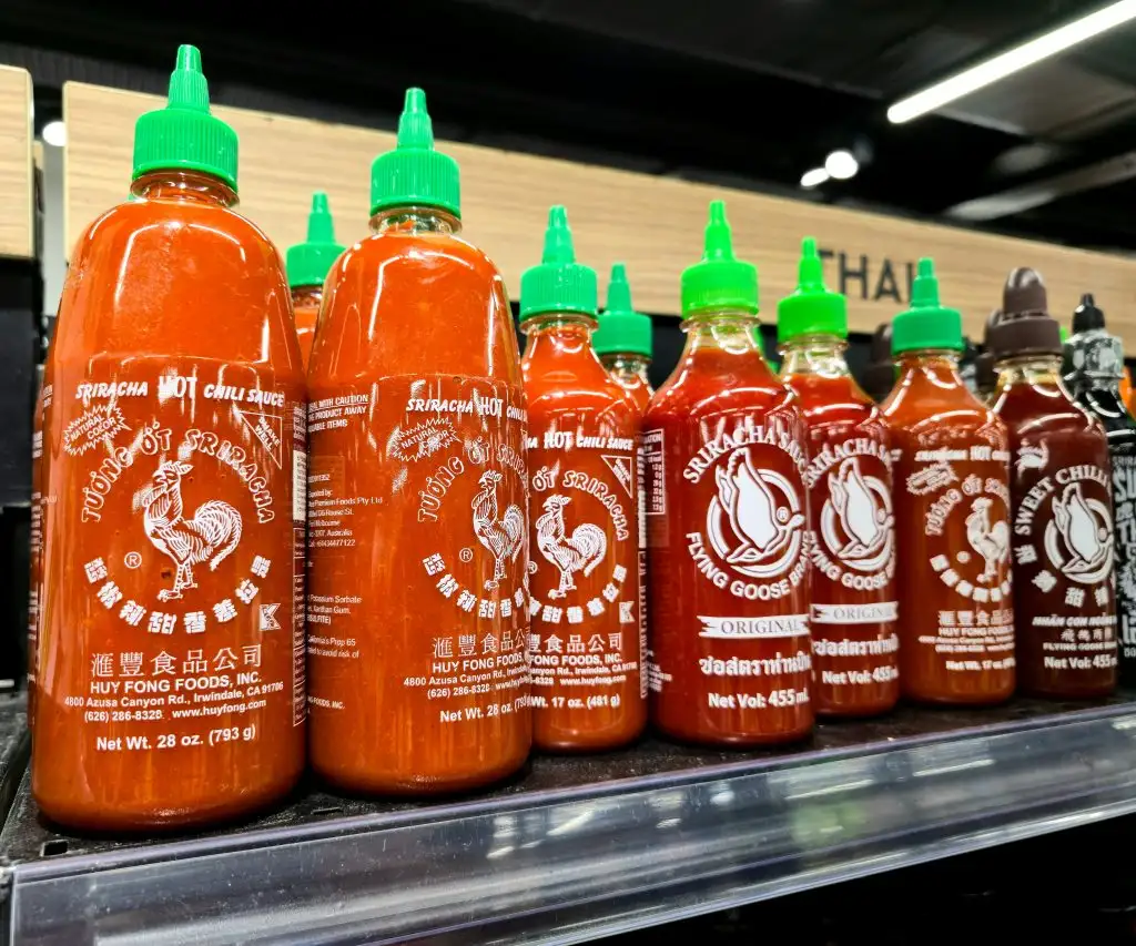 Bottles of Sriracha hot chili sauce lined up on a store shelf
