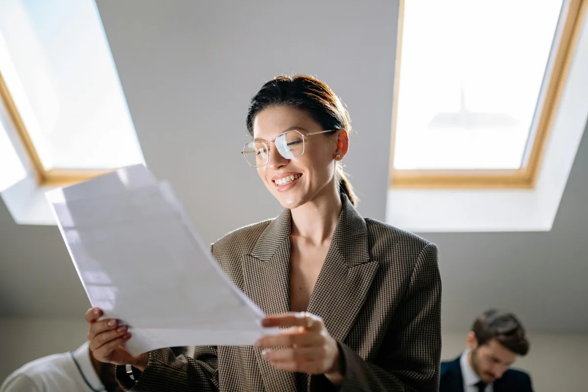 Smiling businesswoman reading printed documents in a modern office