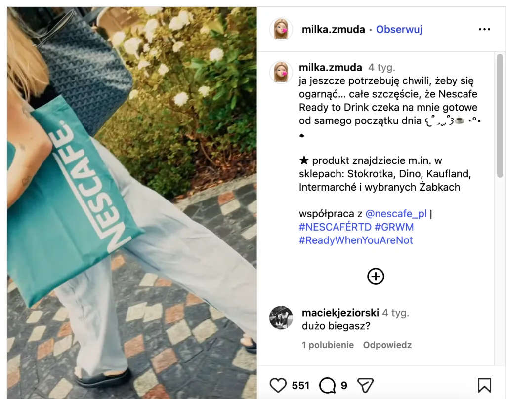 Person carrying a turquoise Nescafé shopping bag while walking outdoors on a sunny day.